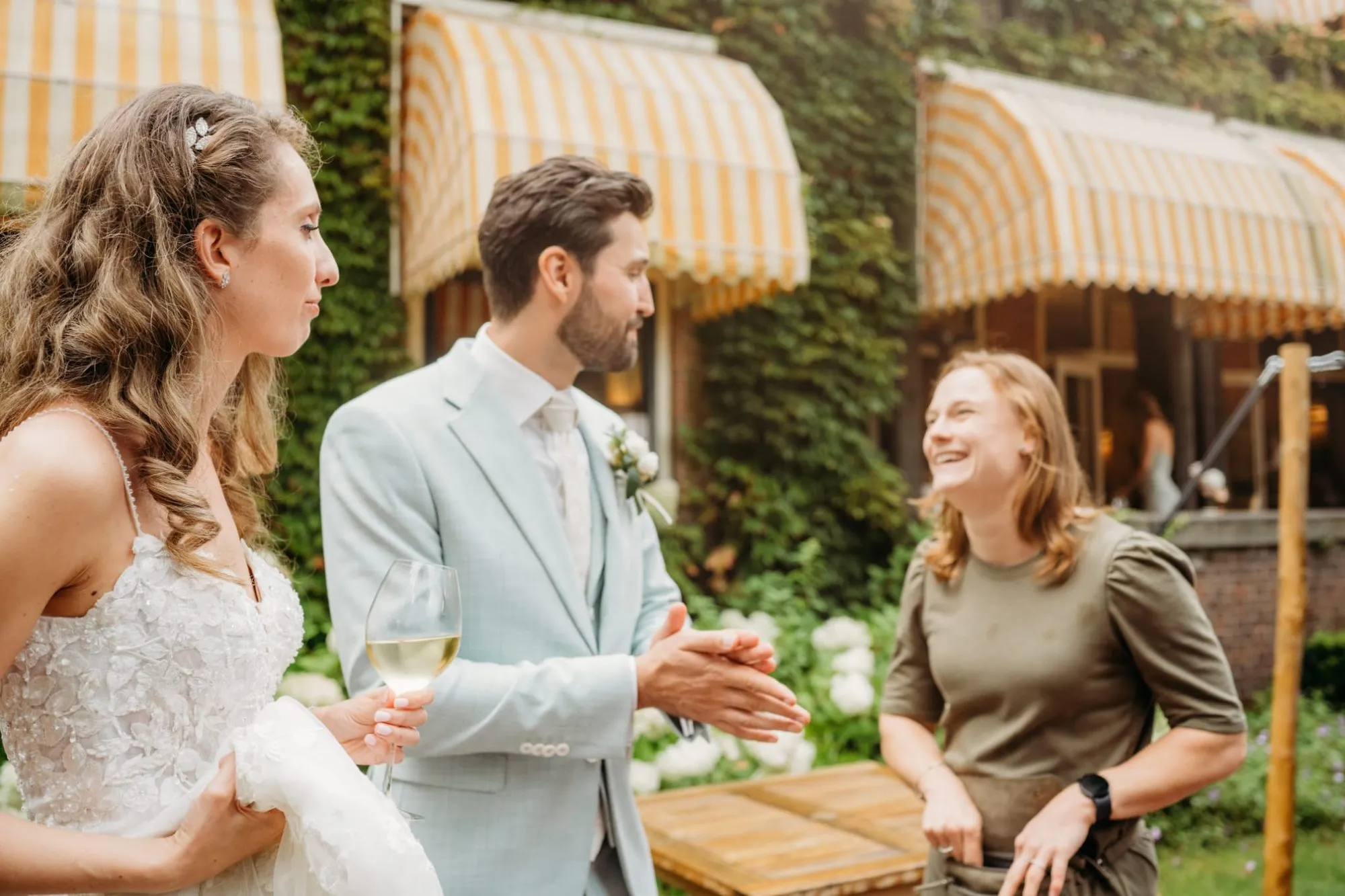 Bruid en bruidegom lachen met Kirsten op een terras