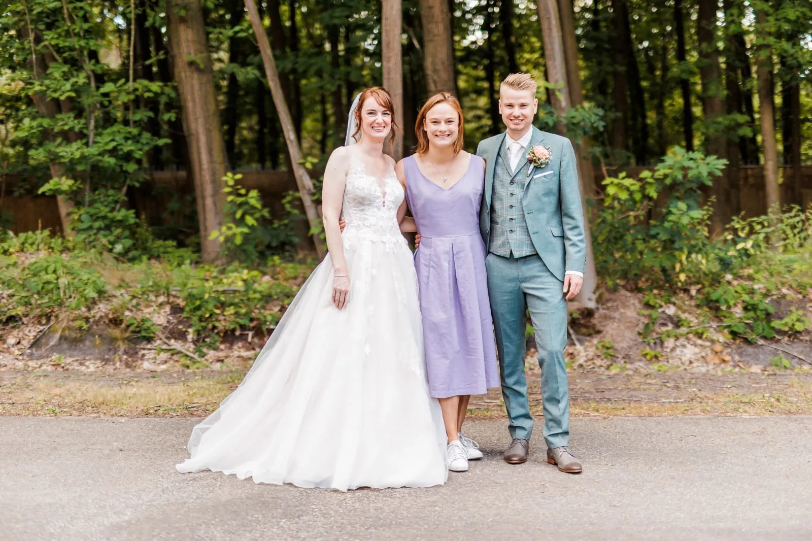 Kirsten tussen bruid en bruidegom voor de bomen