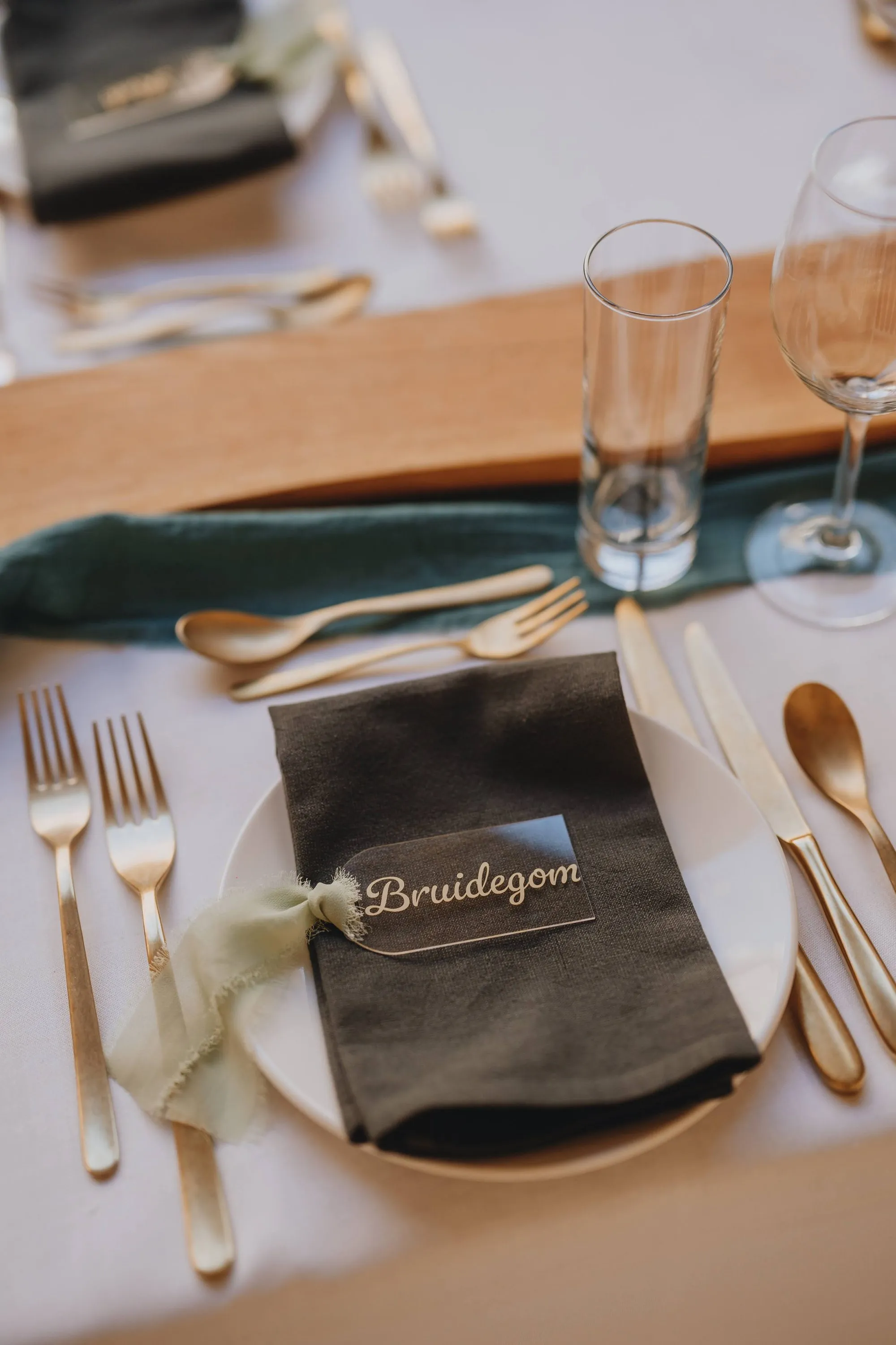 Naamplaatje met 'Bruidegom' op een servet, naast gouden bestek