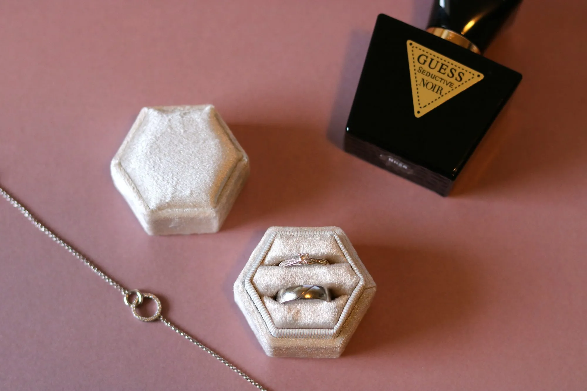 Velvet ringendoosje met twee ringen, naast een ketting en een parfumflesje